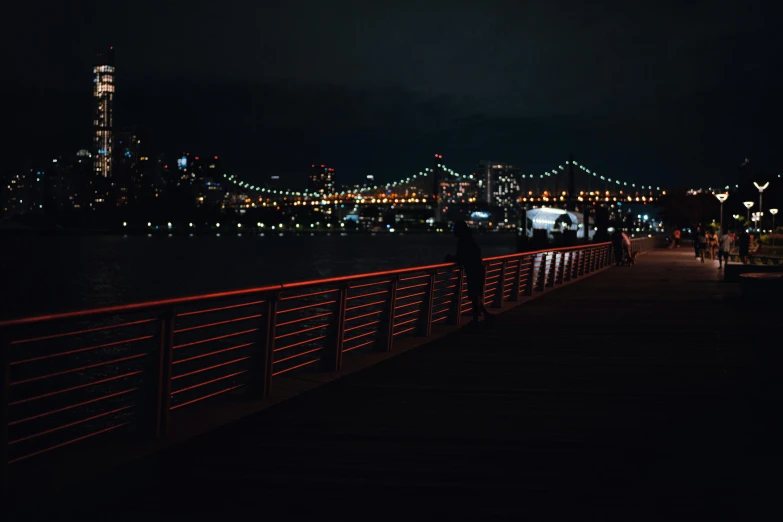 a person standing next to a fence near the water at night