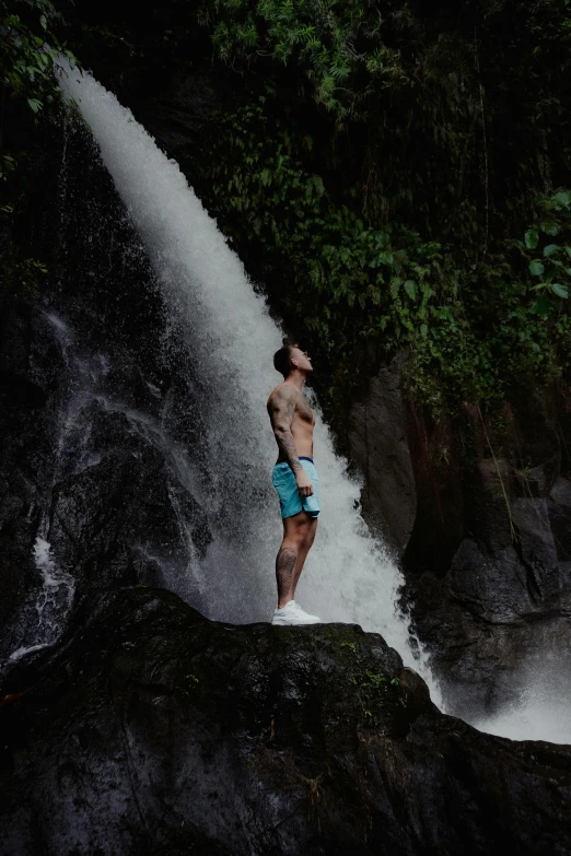 a man standing on a waterfall looking up at the water