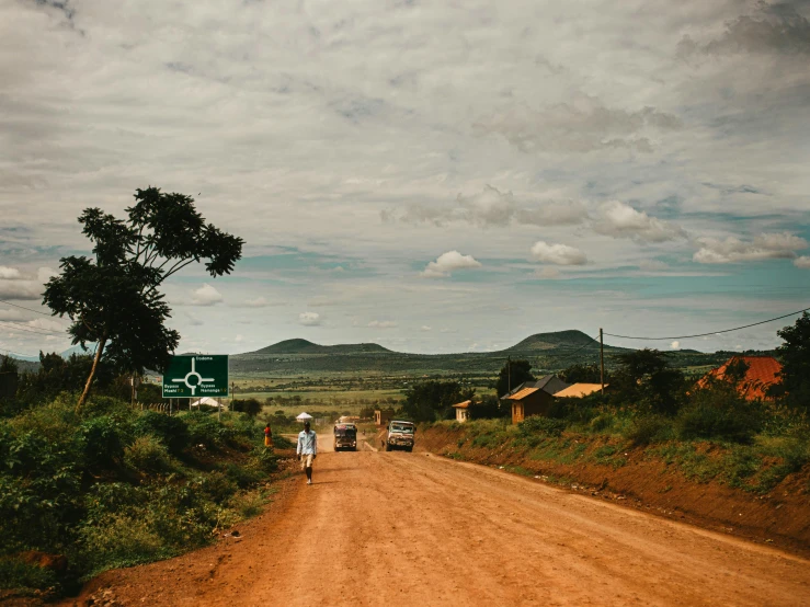 four people walking along side a dirt road