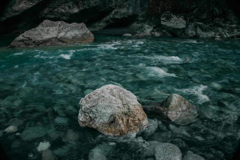 a river flows beneath large rocks as it winds through the water