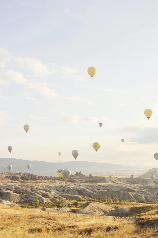 many  air balloons are floating above a dry landscape