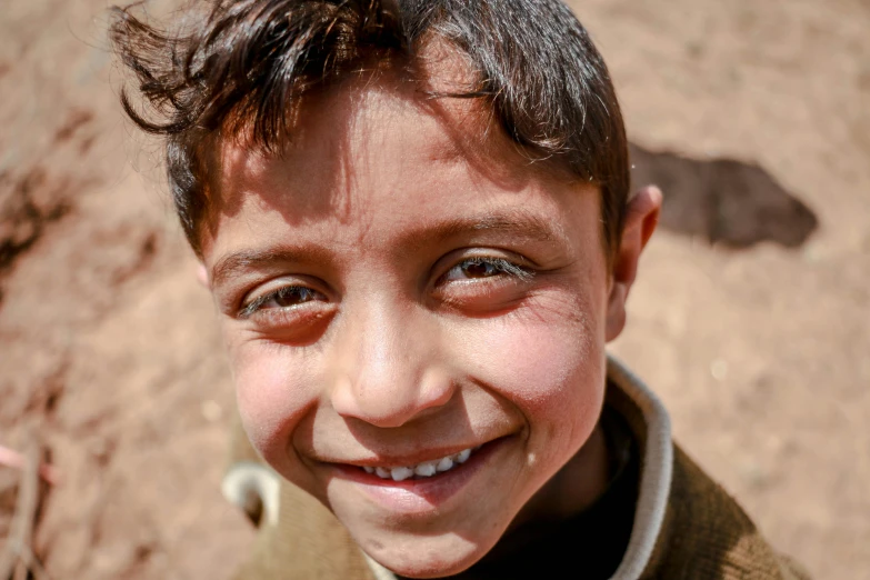 a smiling little boy in a beige shirt