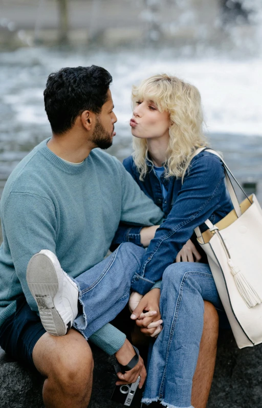 a couple sit together on the beach and look into each other eyes