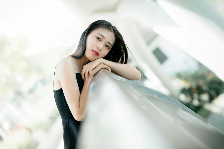 an asian woman leans up against the wall outside