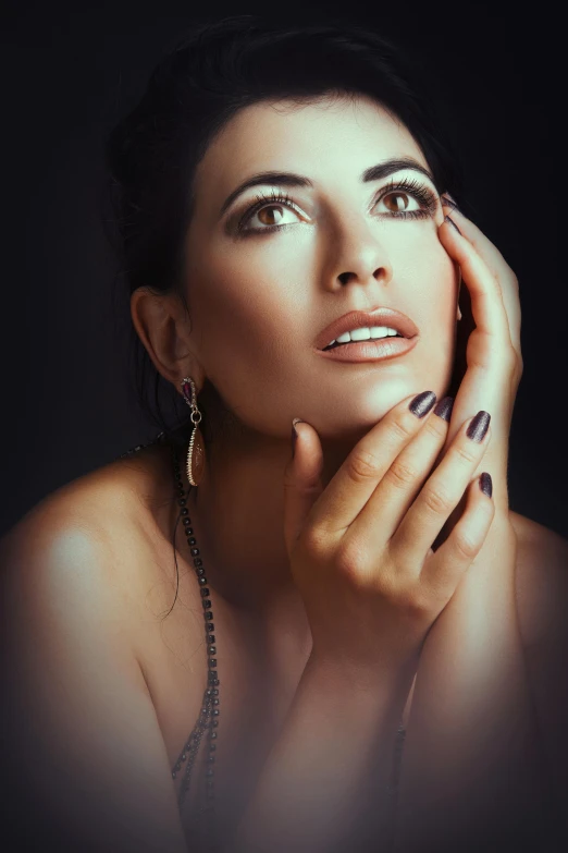 woman in dark lighting with long jewelry and ring