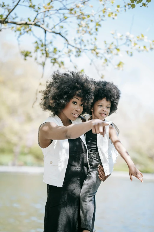 two woman pose with one pointing toward the camera