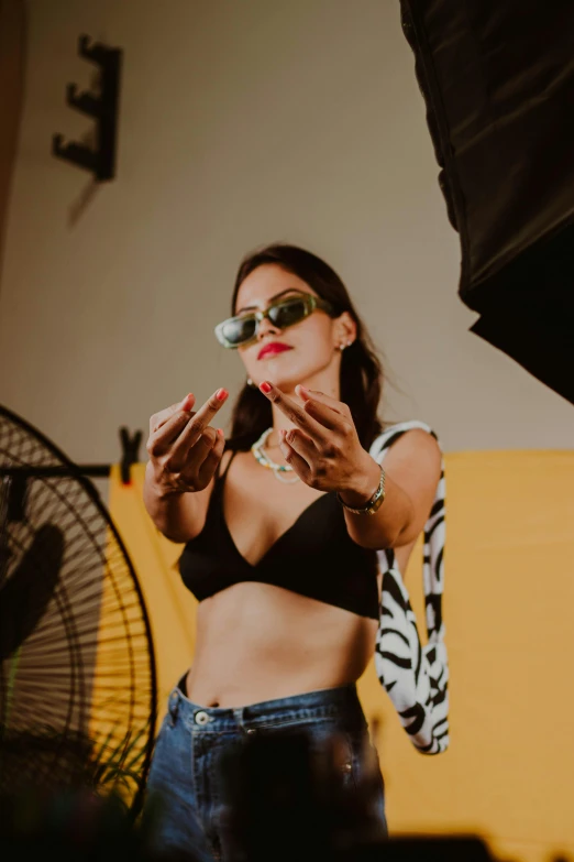 a woman standing in front of a fan holding up her hands