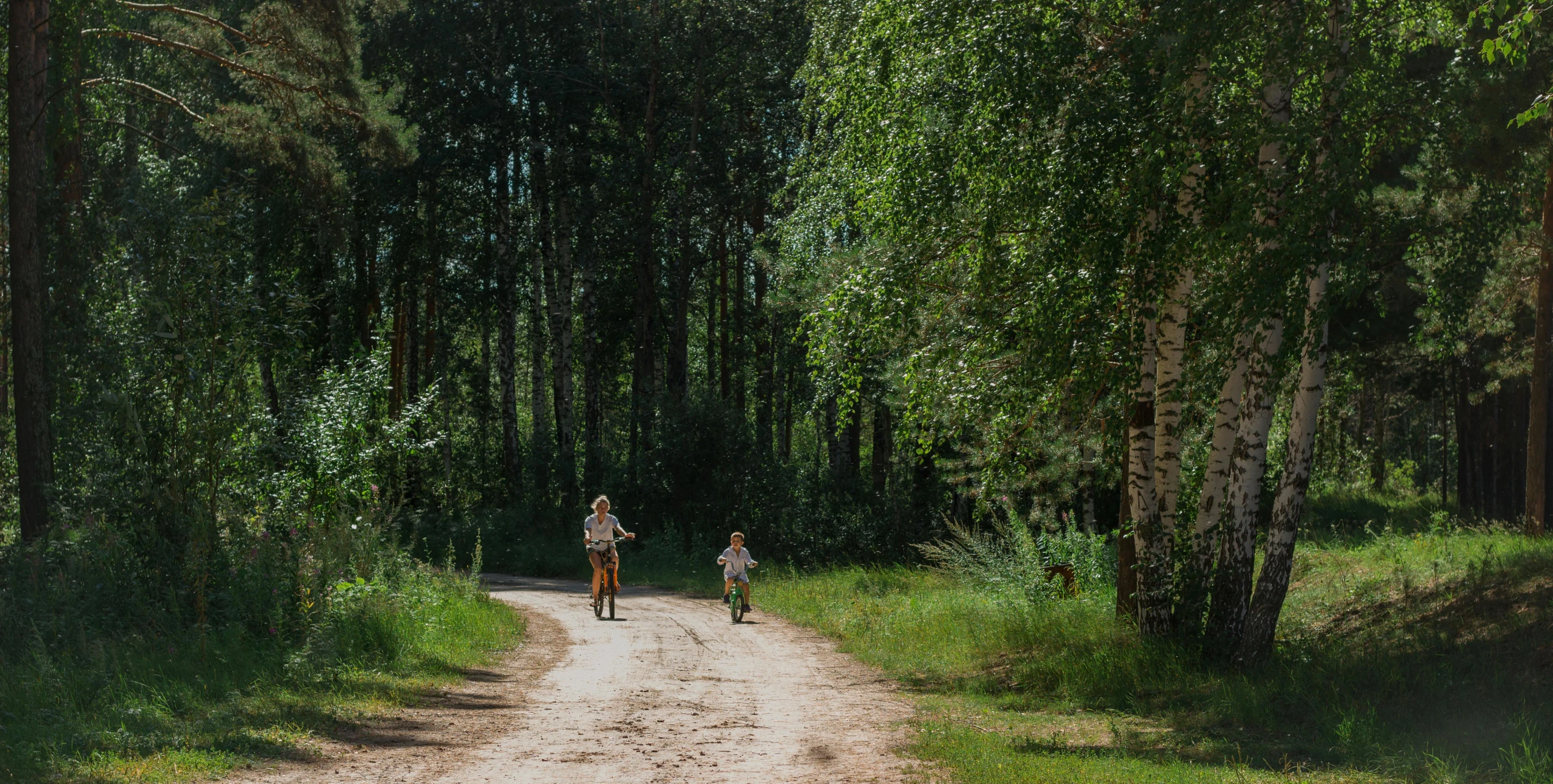 two people on a dirt road, with trees behind them