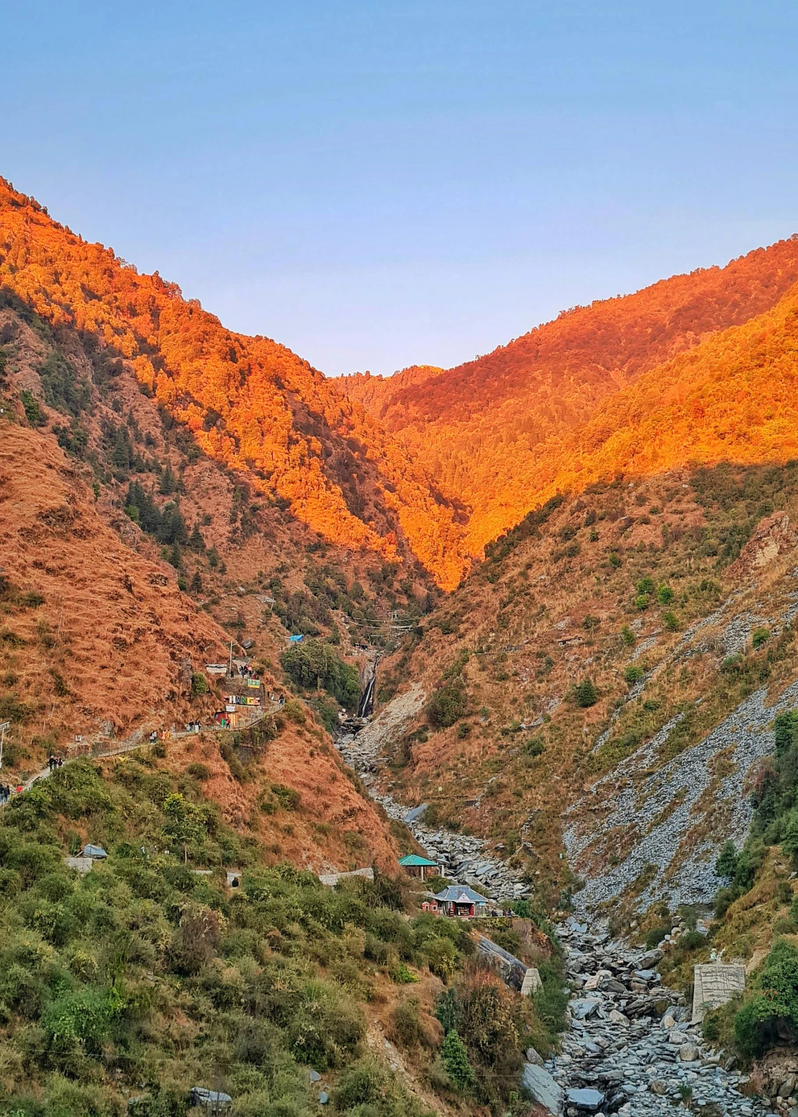 a rocky mountain with orange colors has the trees and rocks and houses