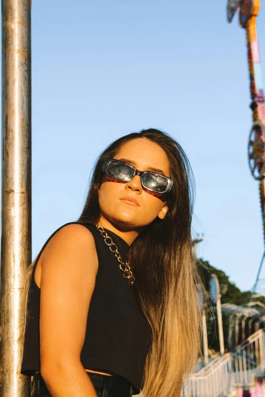 woman wearing sunglasses leaning on a pole outdoors