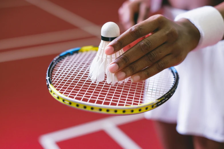 person holding a badminton racket with two shuttles