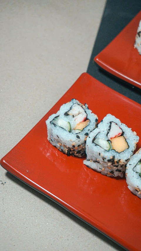 sushi rolls displayed on red plate and tan surface