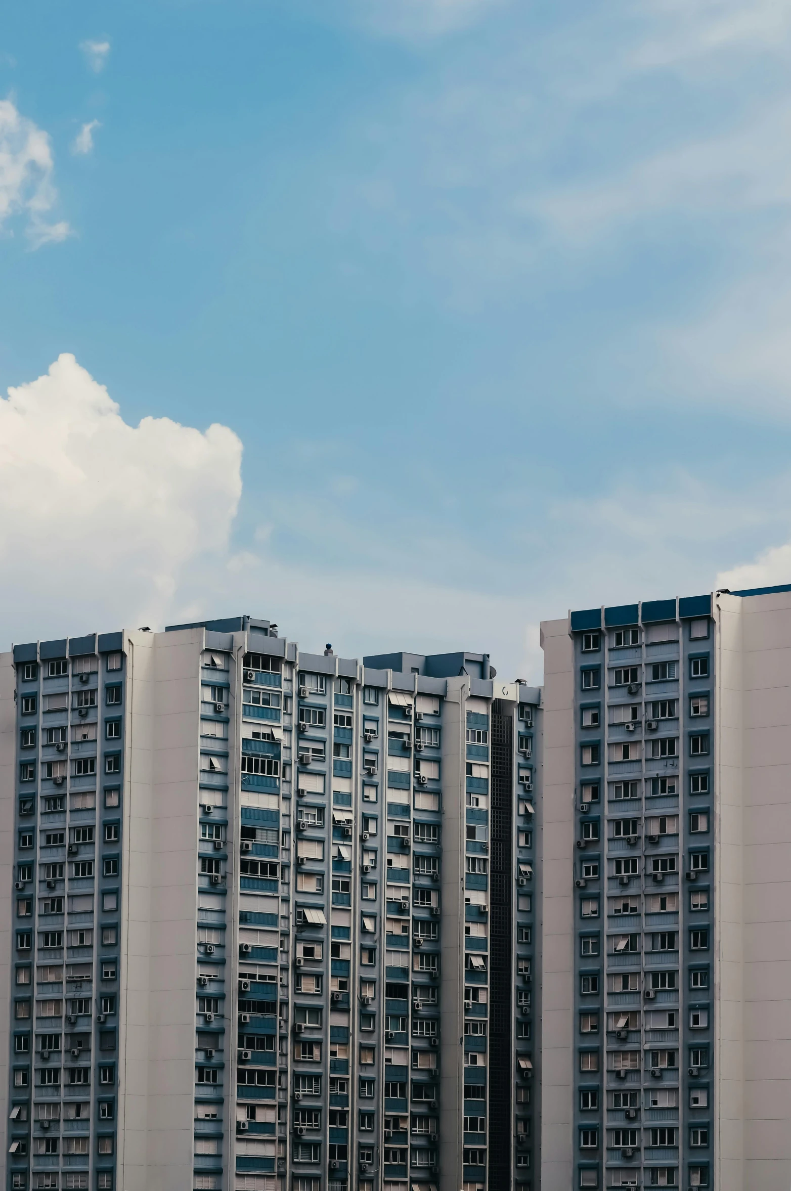 an airplane flying by tall apartment buildings in a cloudy sky