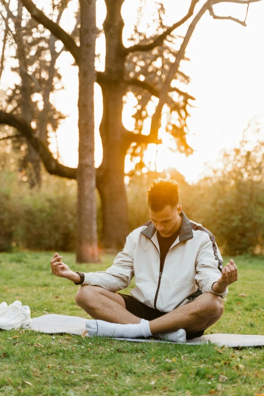 man meditating in the park during sunset