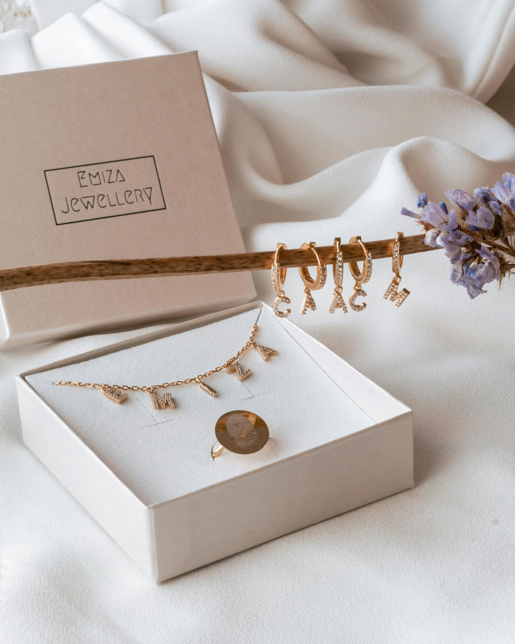 a box and two pieces of jewelry are on a bed