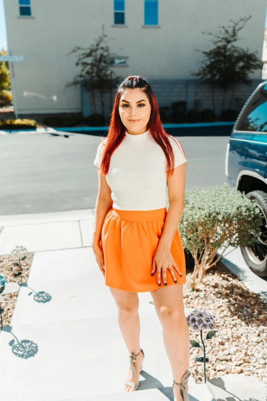 a woman in orange skirt and heels posing for a po