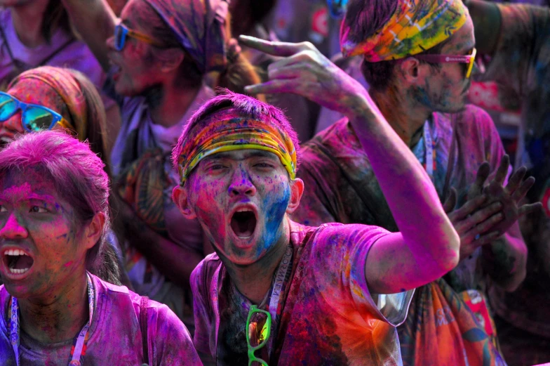 two women and three men all have colored powder on their faces