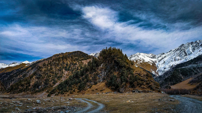 a road between a two mountain peaks covered in snow