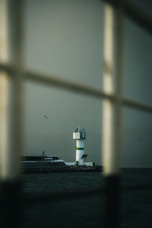 a lighthouse sits on the side of the ocean behind bars