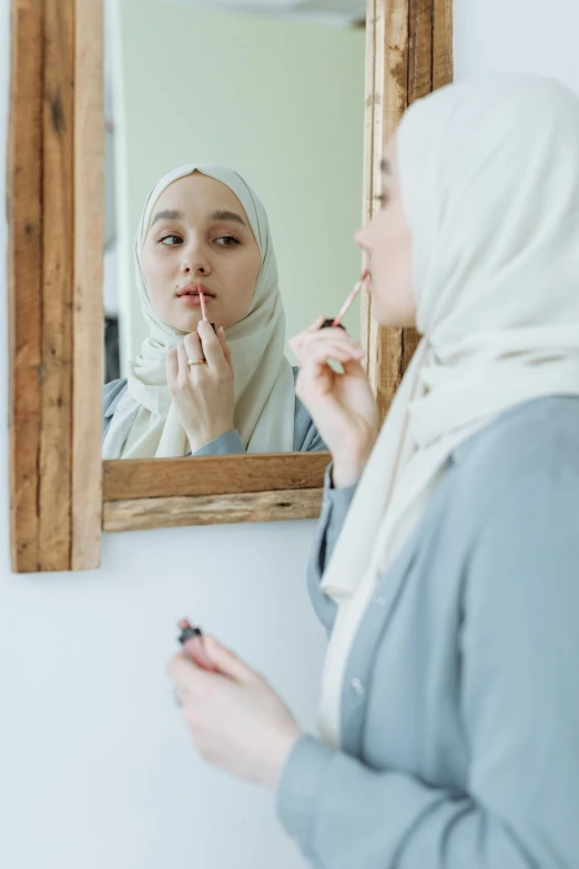 a woman putting lipstick on her lips while looking in the mirror