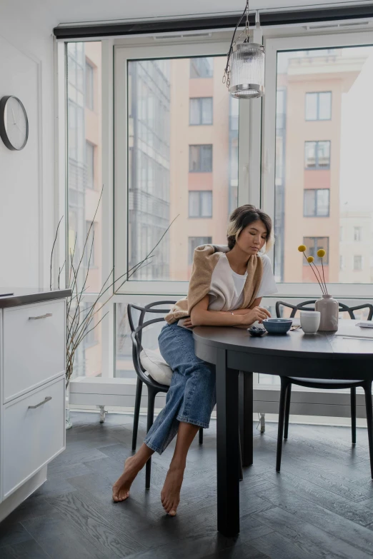 a woman is sitting at the table and is using her cell phone