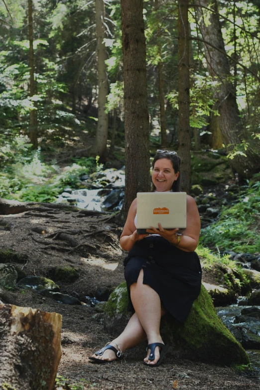 woman sitting in a forest reading a computer