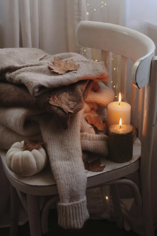 a blanket on top of a chair next to a lit candle