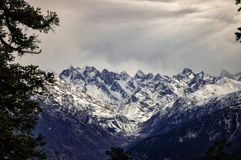 a snow covered mountain range with trees on both sides