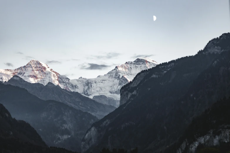 the sun is setting on the snow capped mountains