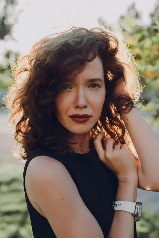 an attractive woman is posing in front of some trees