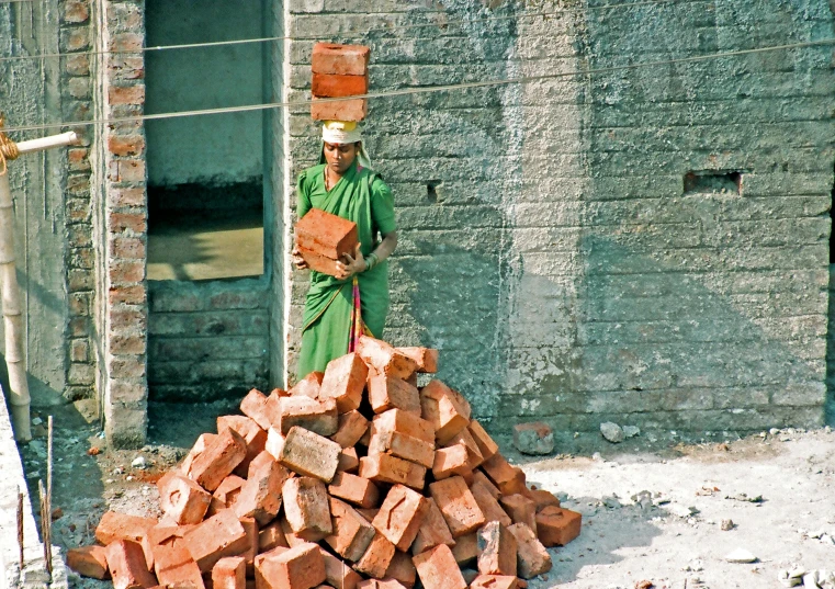 a man standing near a pile of brick with a red brick on top