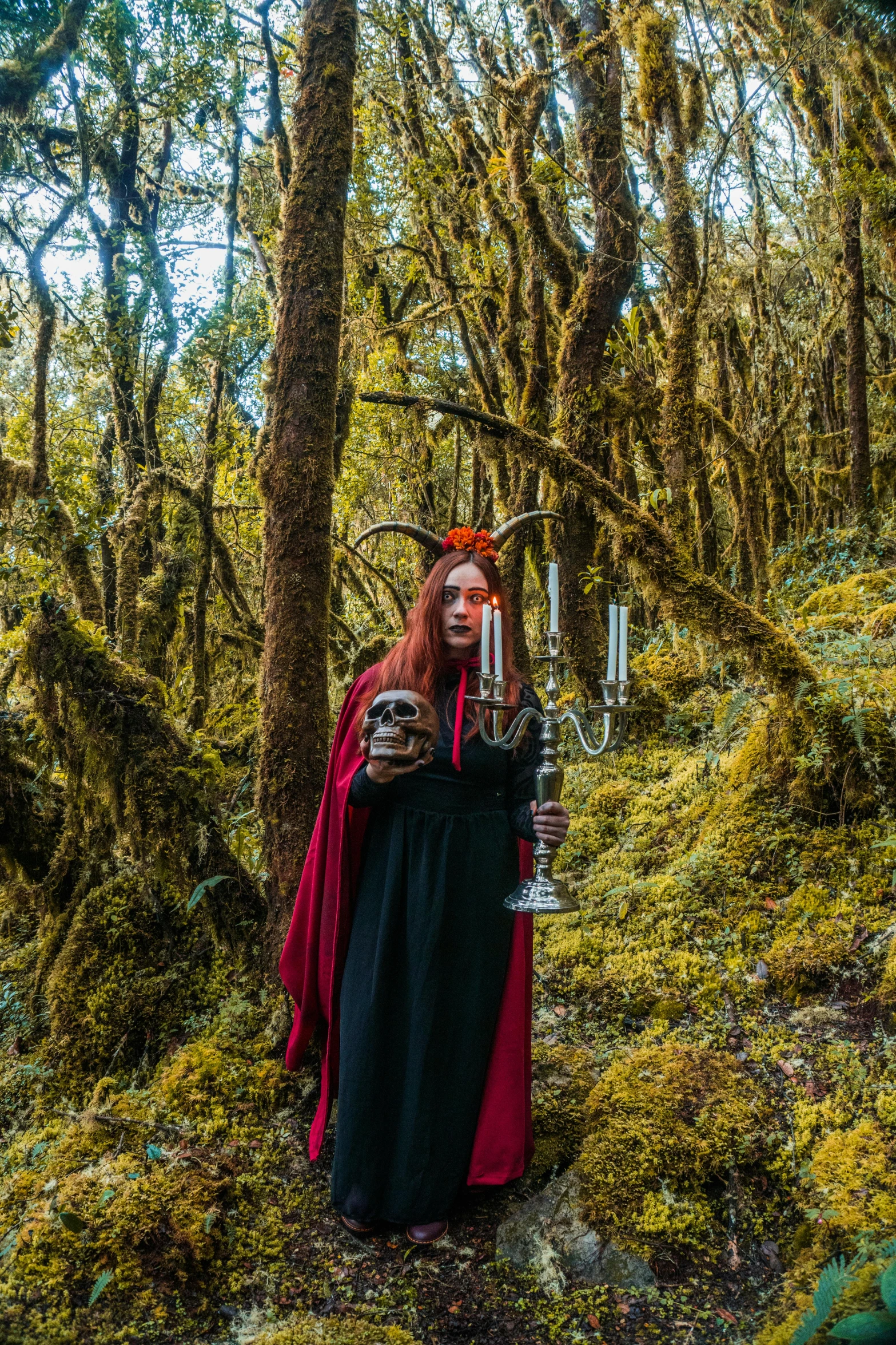 a red haired woman standing in the woods holding an object