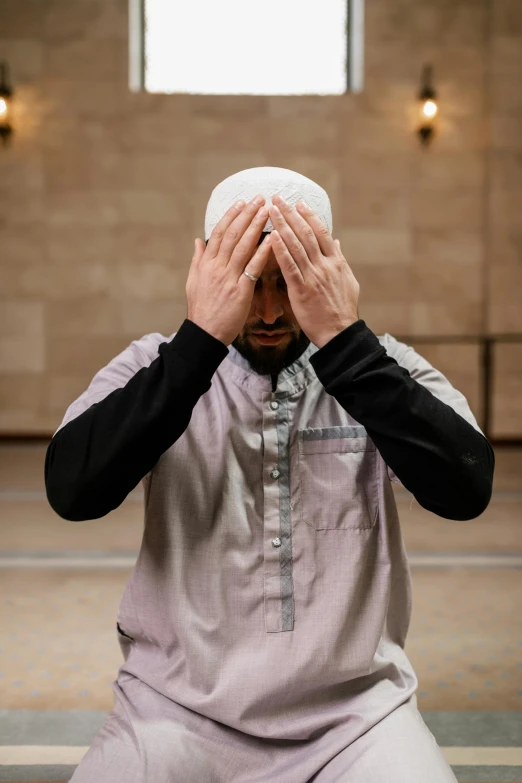 a man sitting down holding his hands to his head