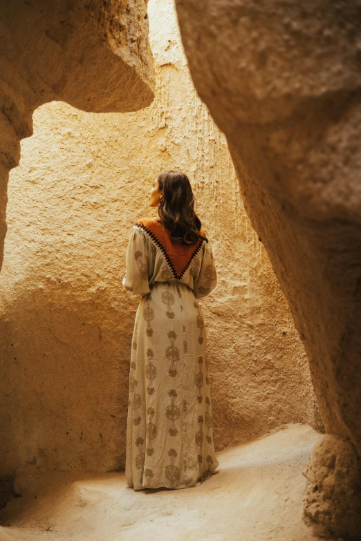 a woman standing in front of some rocks and sand