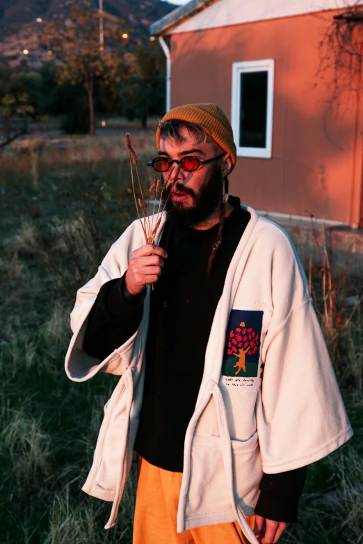 a man wearing sunglasses holding some dried plants