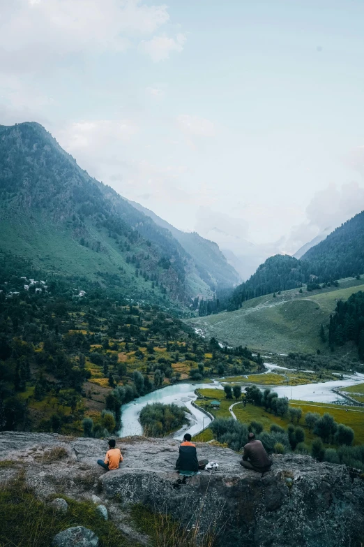 a man and woman sitting at a cliff overlooking the valley