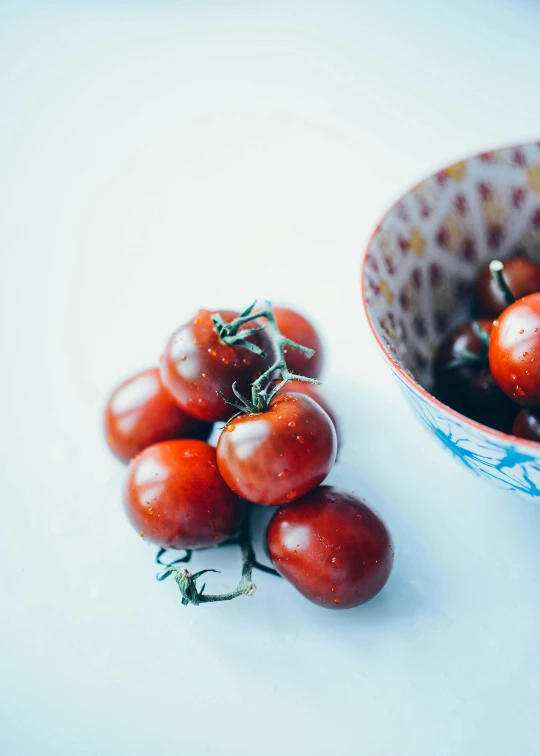 bowl of small red tomatoes sitting on a white counter top