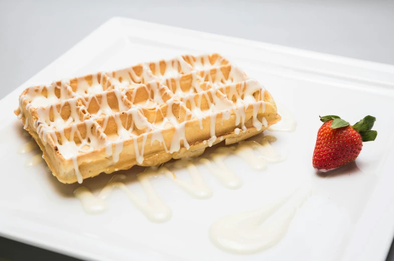 a waffle is on a white plate next to a strawberry