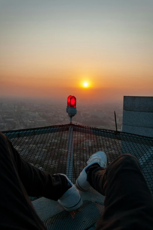 a man looks over a bridge at the sun setting