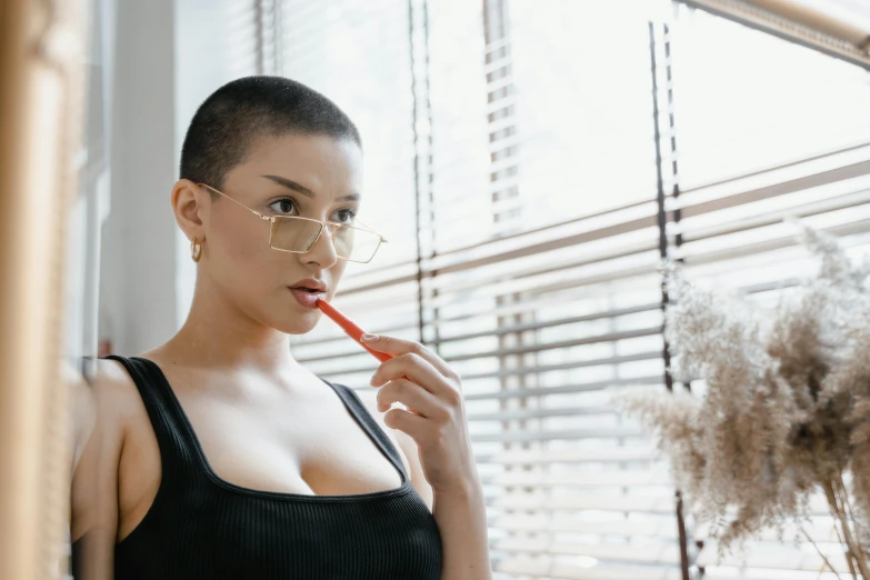 woman brushing her teeth with a toothbrush next to a window