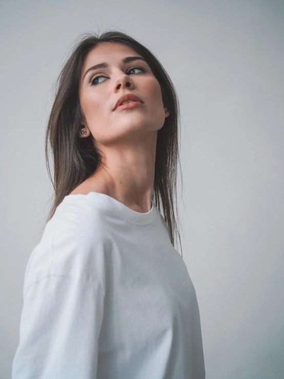 woman wearing a white top looks up into the sky