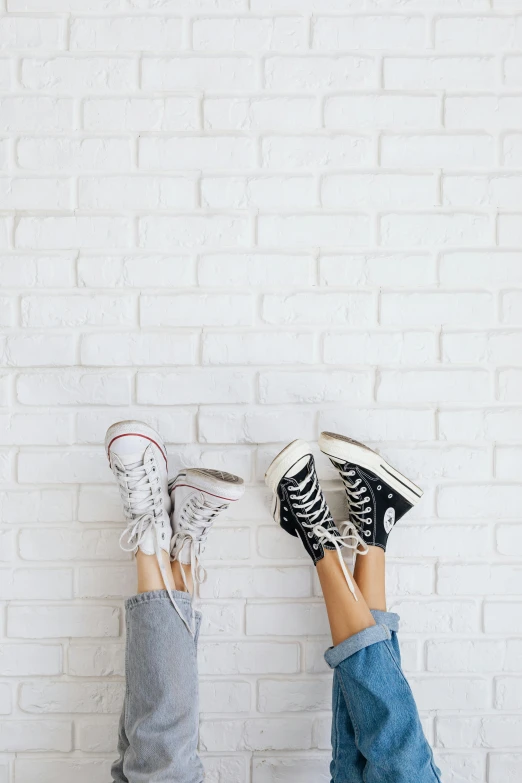 two people with their feet up against a brick wall