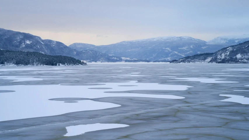 an ice lake in front of snowy mountains