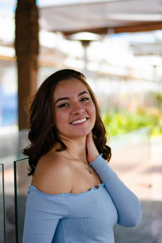 woman smiling as she leans against the glass door of a building