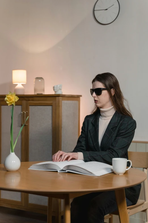 a woman is sitting at a wooden table and reading