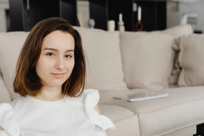 a woman in a white shirt is sitting next to a couch