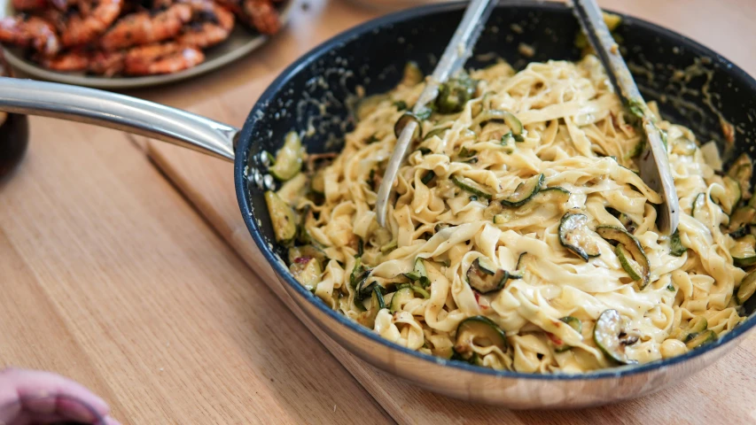 pasta with a lot of cheese and green onions is in the bowl