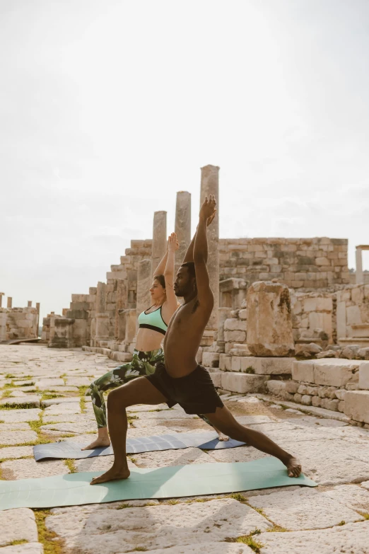 a man in a yoga pose near some ruins