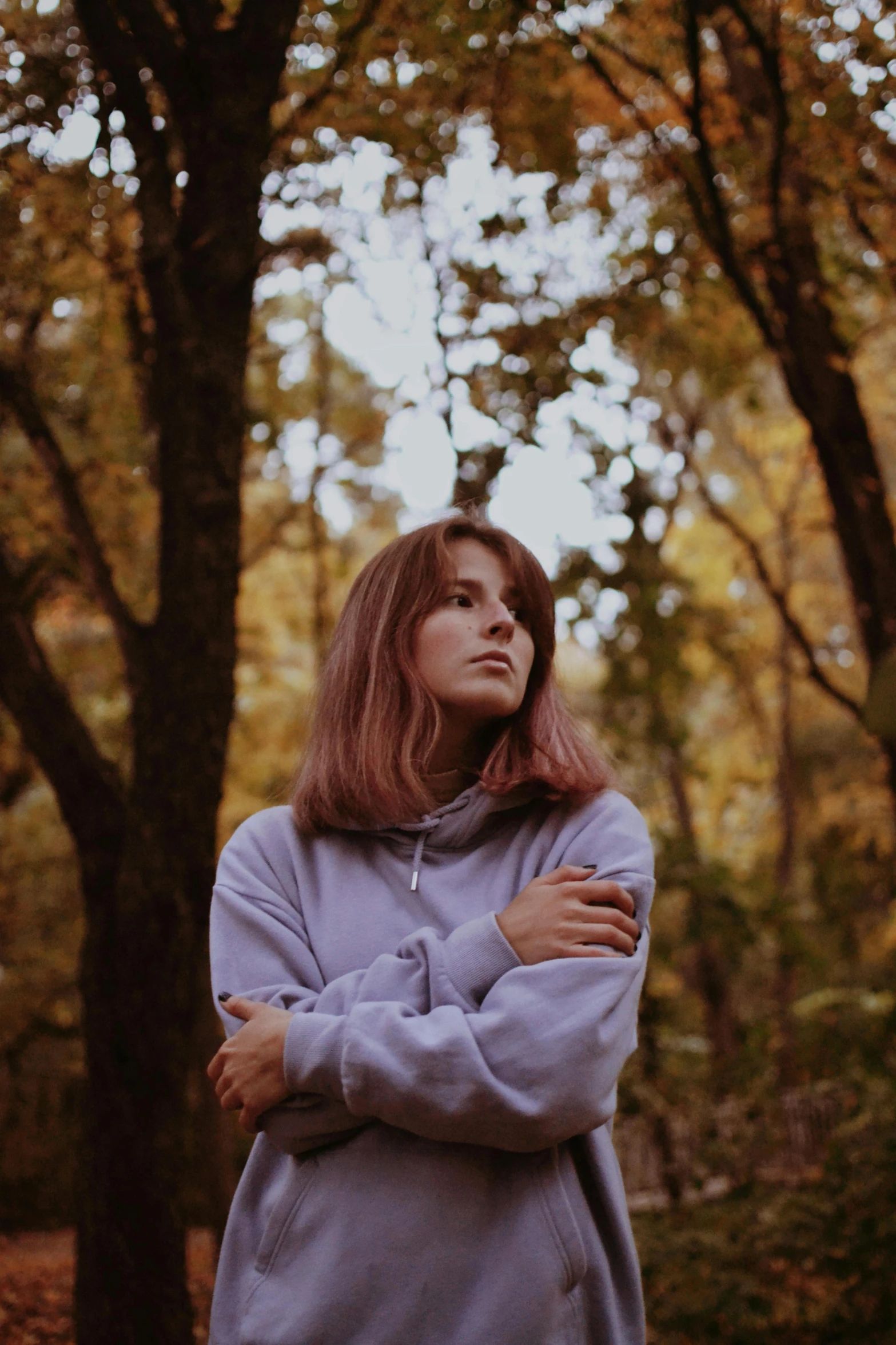 a woman is standing in the woods looking up