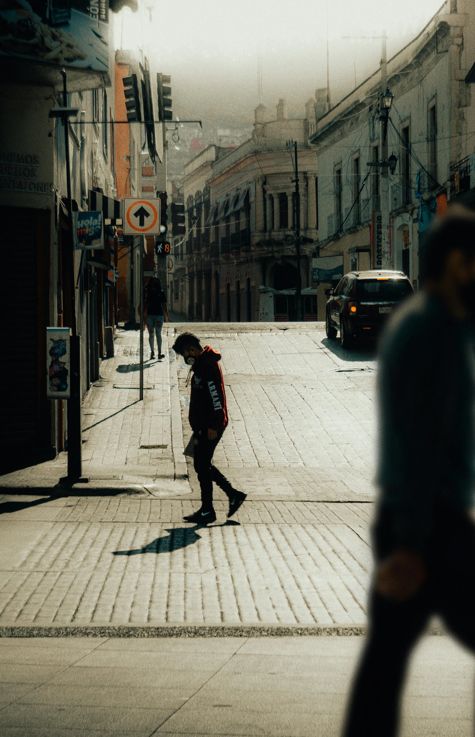 a guy walking across a city street carrying a bag